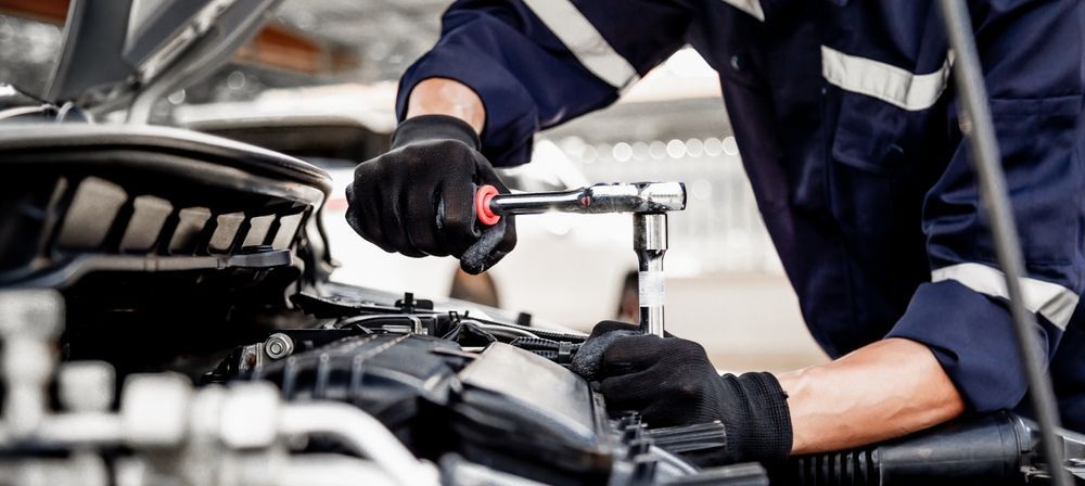 A Man Is Working On A Car Engine With A Wrench — Advanced Windscreens & Service Centre In Proserpine, QLD