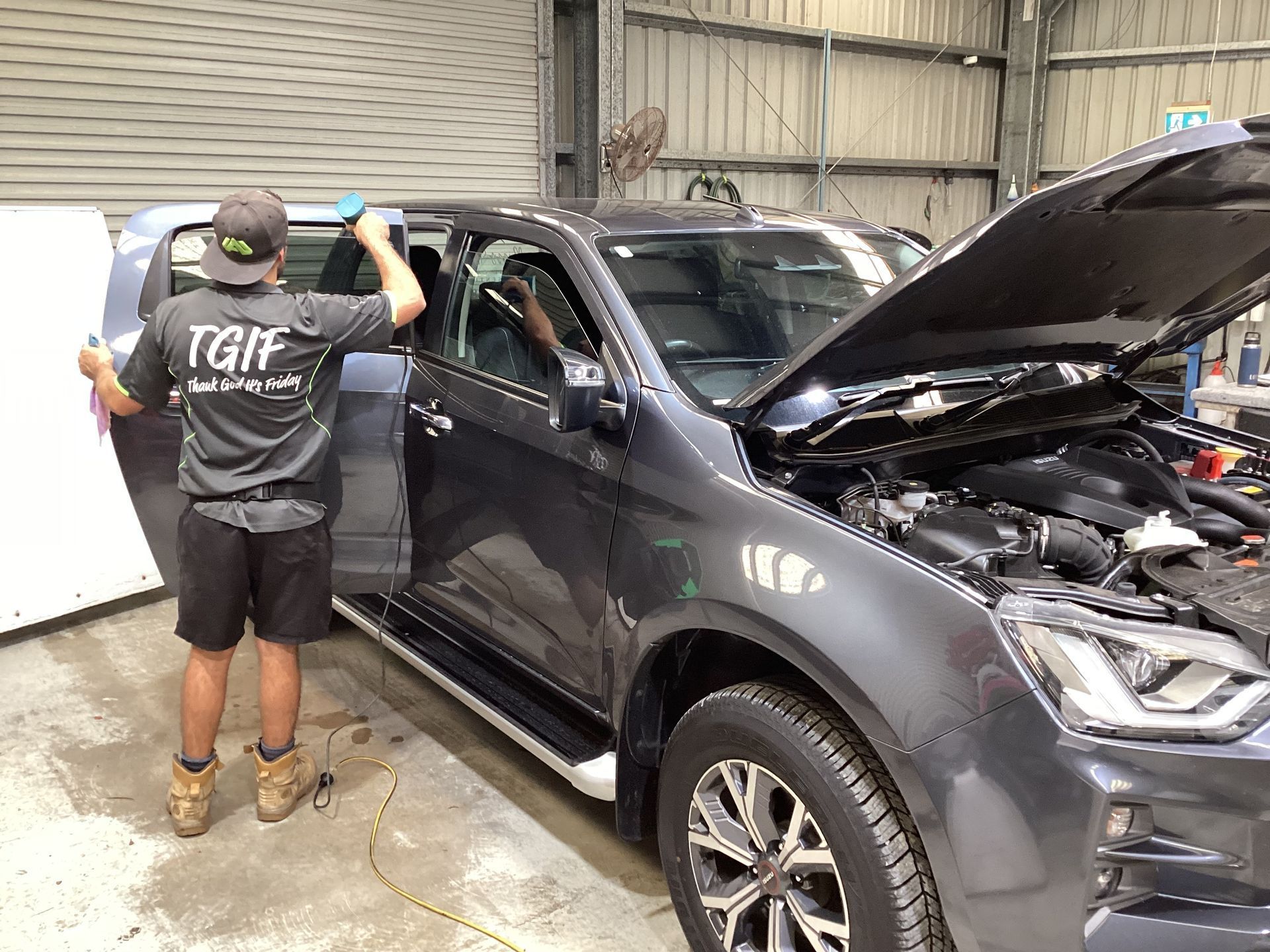 A Man Is Applying Tinted Window Film To A Car Window— Advanced Windscreens & Service Centre In Whitsunday Region, QLD