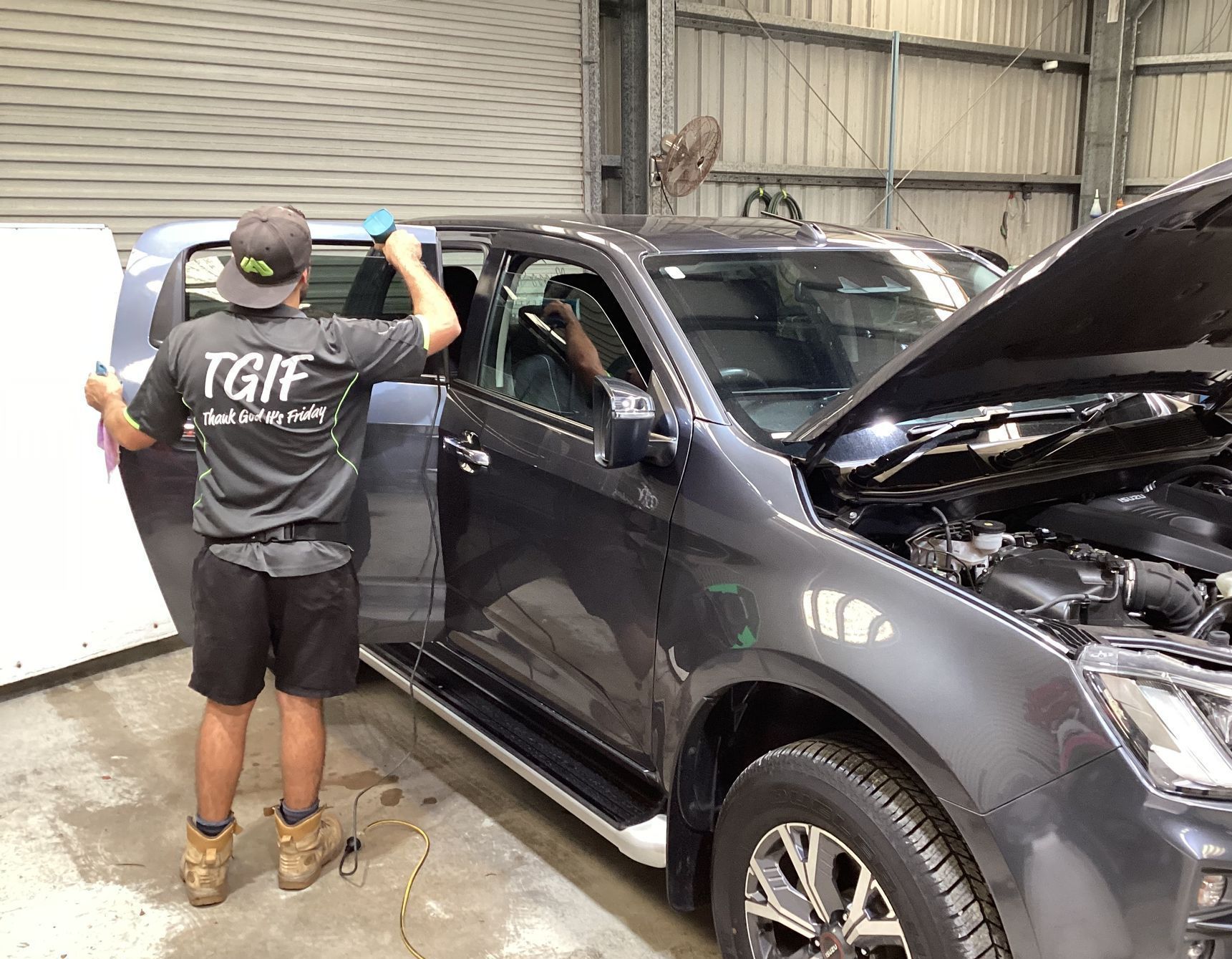 A Man Is Applying Tinted Window Film To A Car Window — Advanced Windscreens & Service Centre In Bowen, QLD