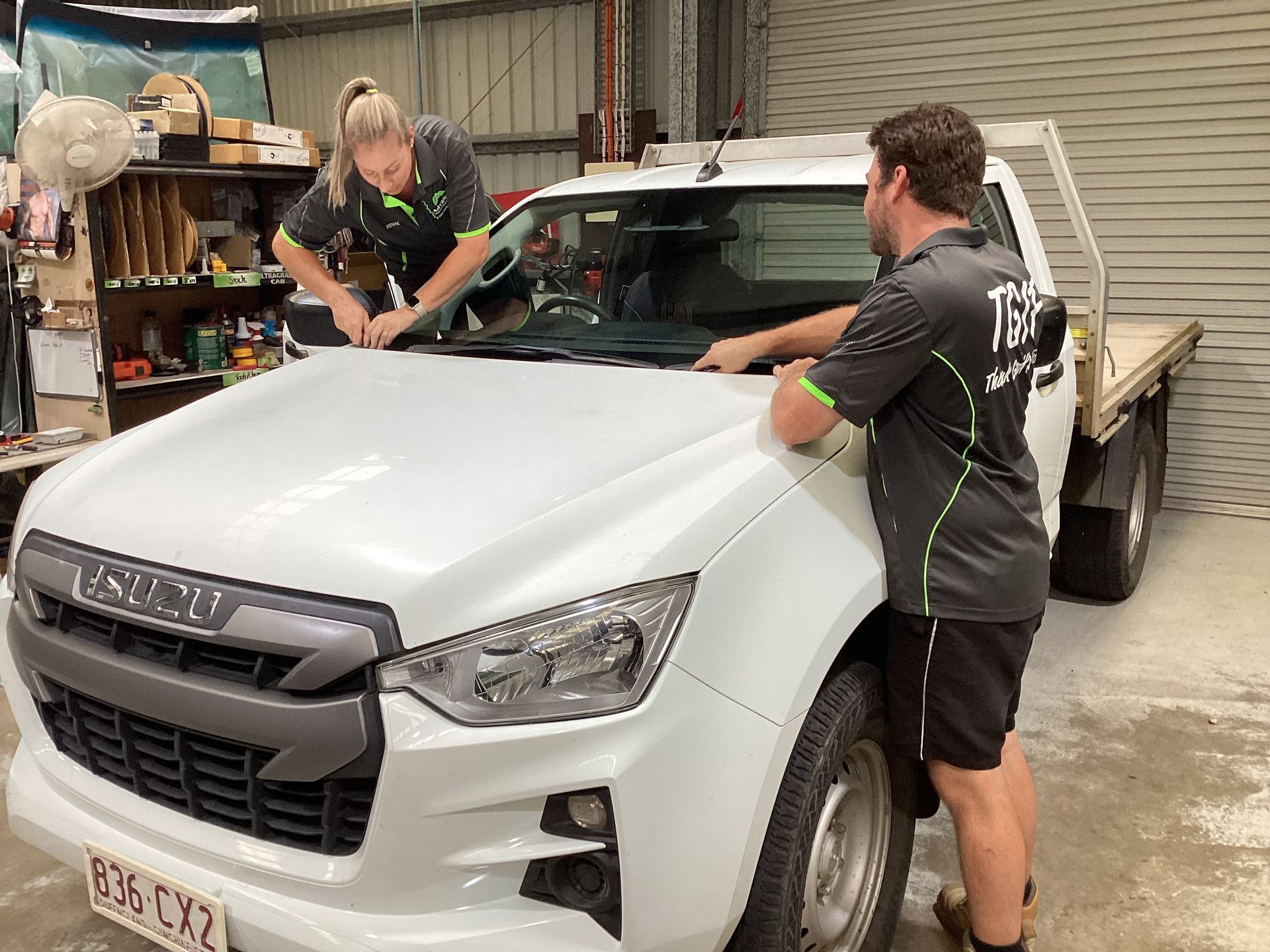 Two People Are Replacing A Windscreen On A Car Engine In A Garage — Advanced Windscreens & Service Centre In Whitsunday Region, QLD