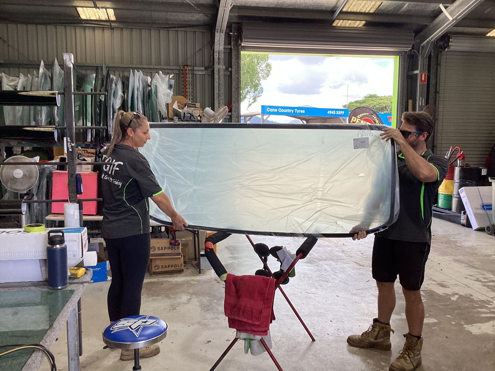 A Man And Woman Holding A Windscreen — Advanced Windscreens & Service Centre In Proserpine, QLD