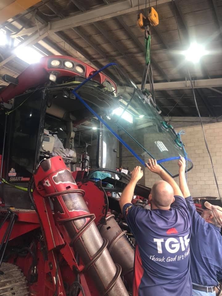 A Group Of Men Are Working On A Combine Harvester In A Garage — Advanced Windscreens & Service Centre In Bowen, QLD