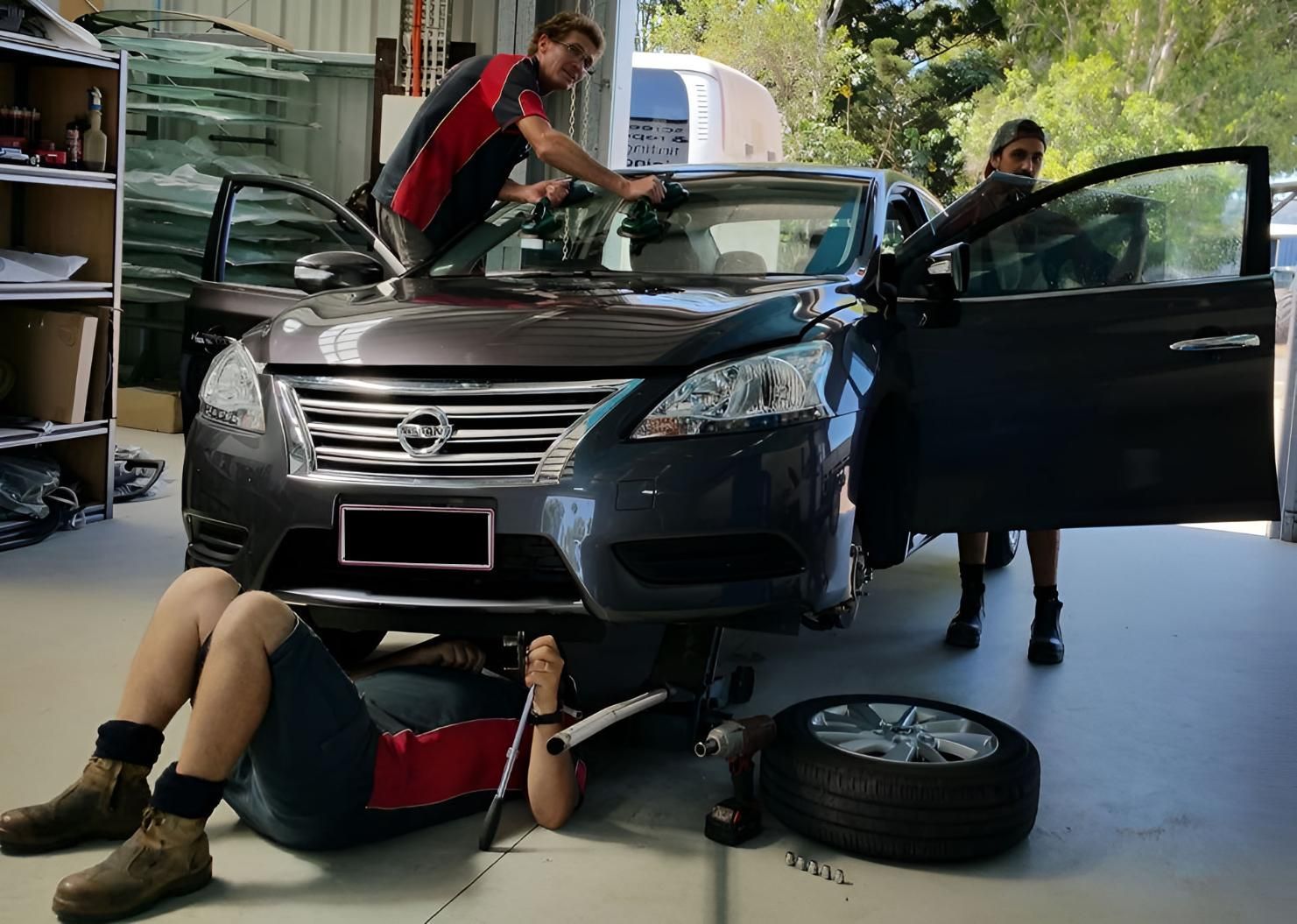 A Group Of People Are Working On A Car In A Garage — Advanced Windscreens & Service Centre In Airlie Beach, QLD