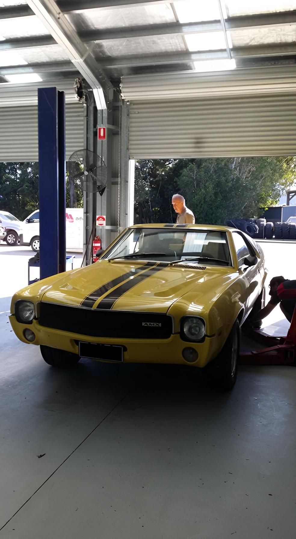 A Man Is Working On A Yellow Car In A Garage — Advanced Windscreens & Service Centre In Proserpine, QLD