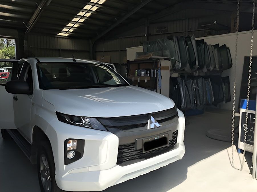 A White Mitsubishi Triton Truck Is Parked In A Garage — Advanced Windscreens & Service Centre In Proserpine, QLD