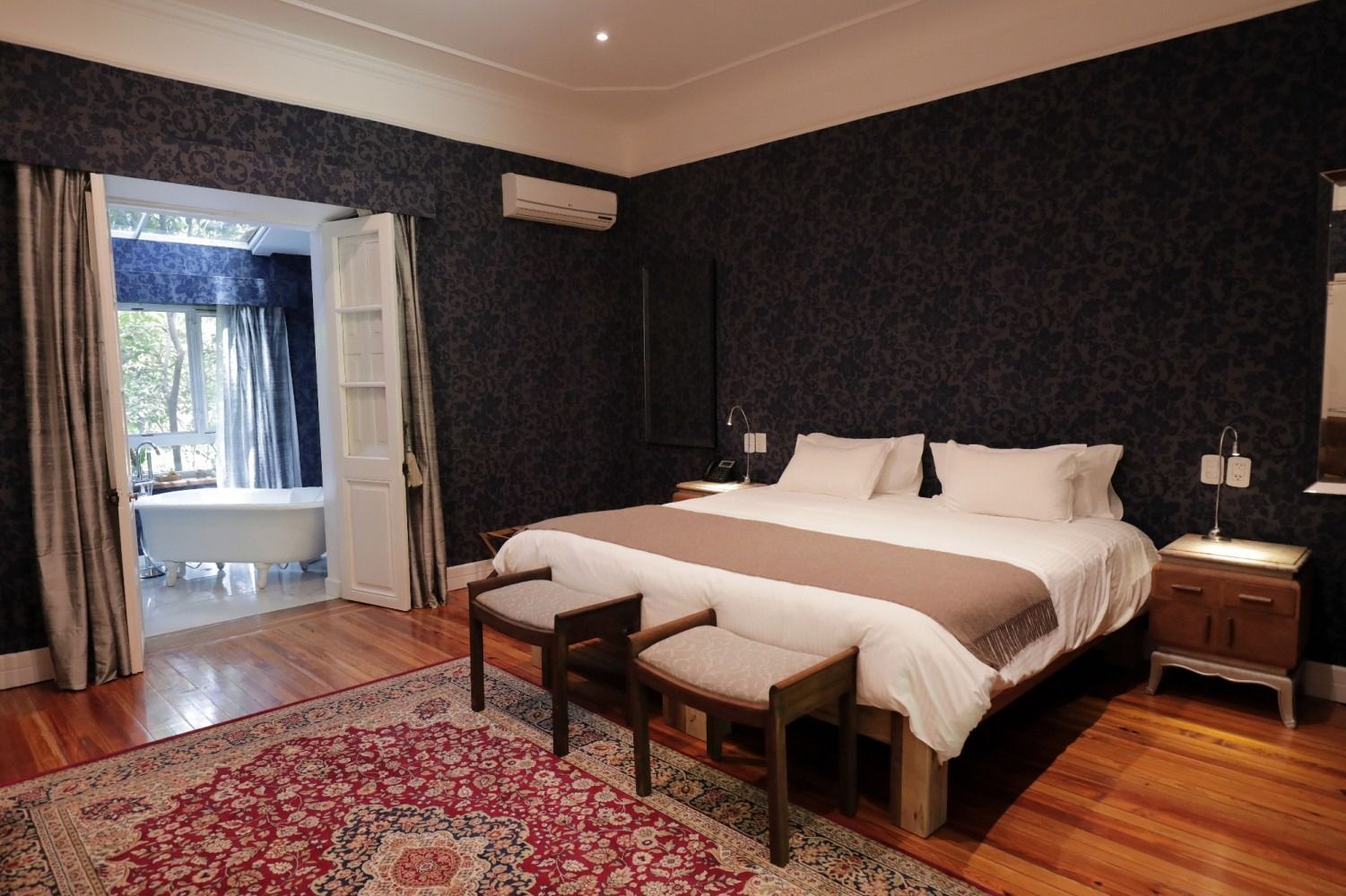 Bedroom with a large bed, two benches at the foot.