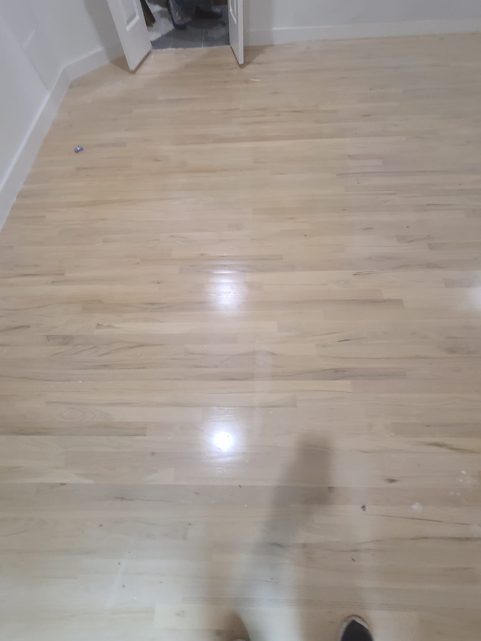 A person is standing on a wooden floor in a room.