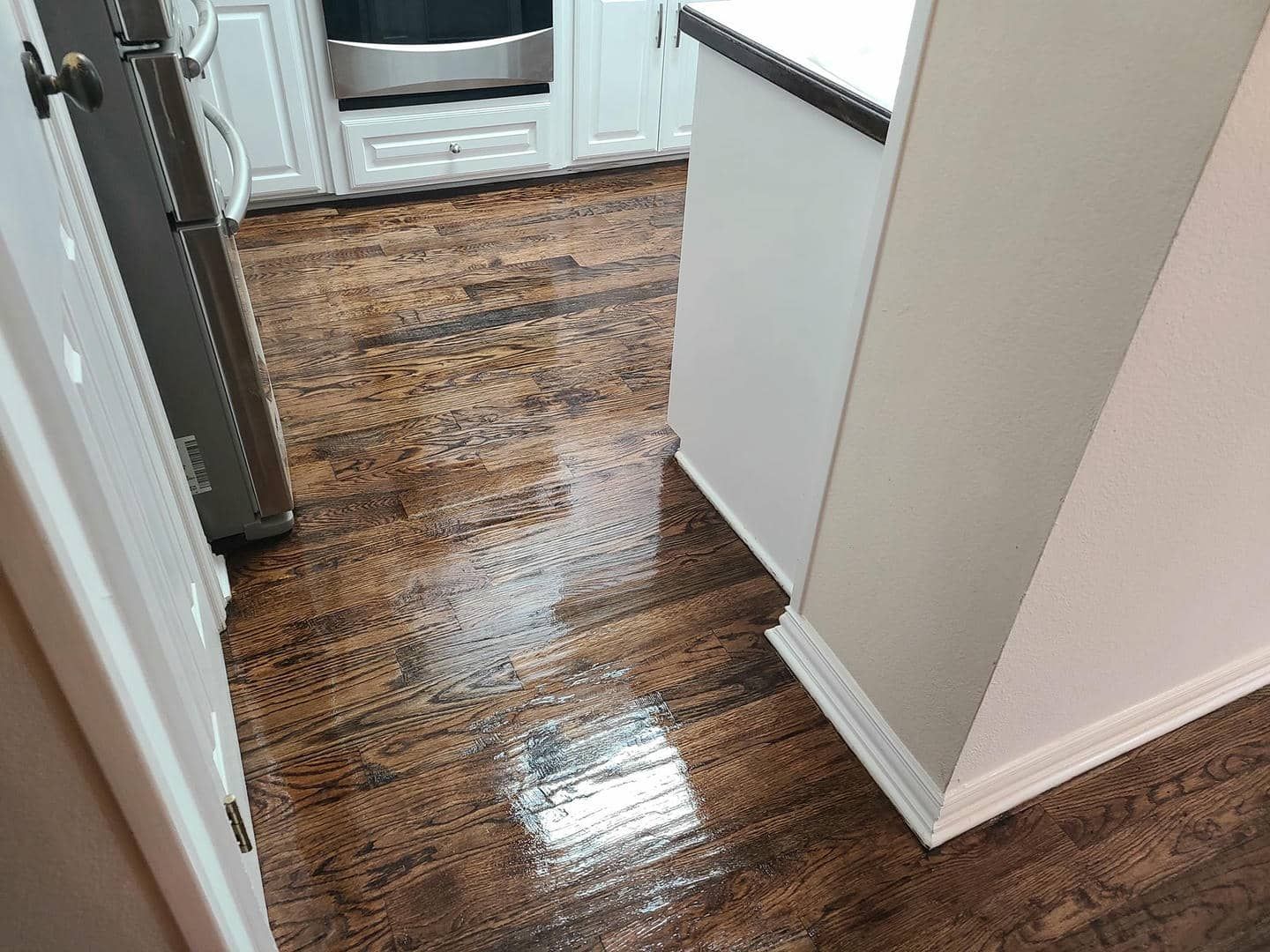 A kitchen with hardwood floors and white cabinets.