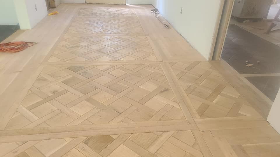 A wooden floor with a geometric pattern in a hallway.
