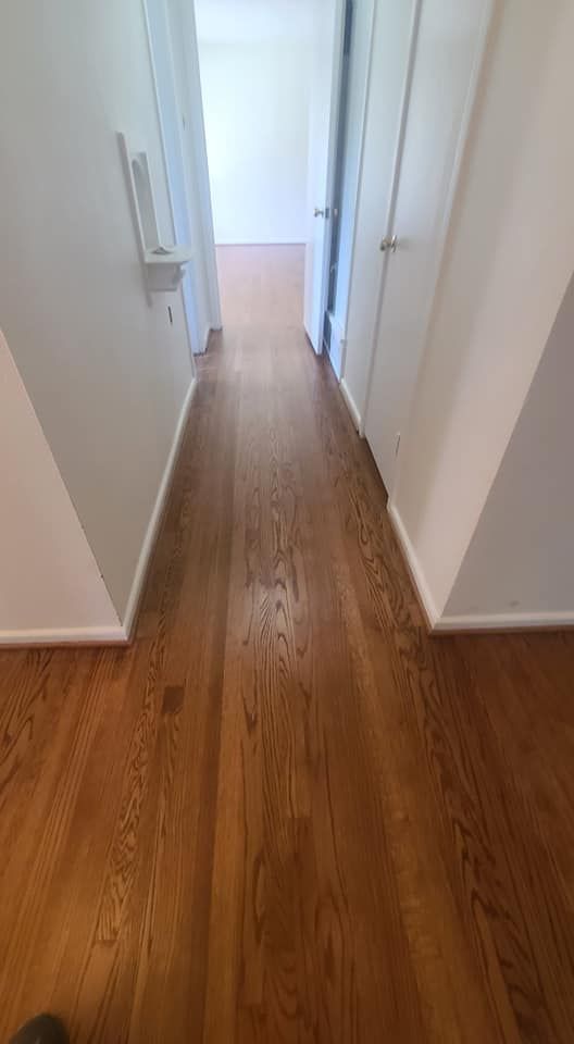 A hallway with hardwood floors and white walls in a house.