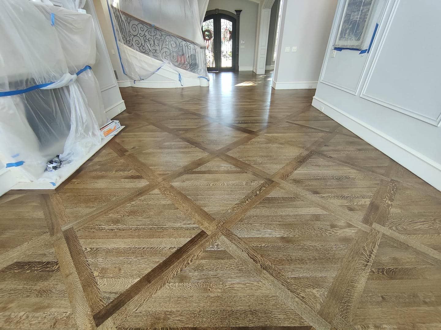 A wooden floor with a geometric pattern in a hallway.