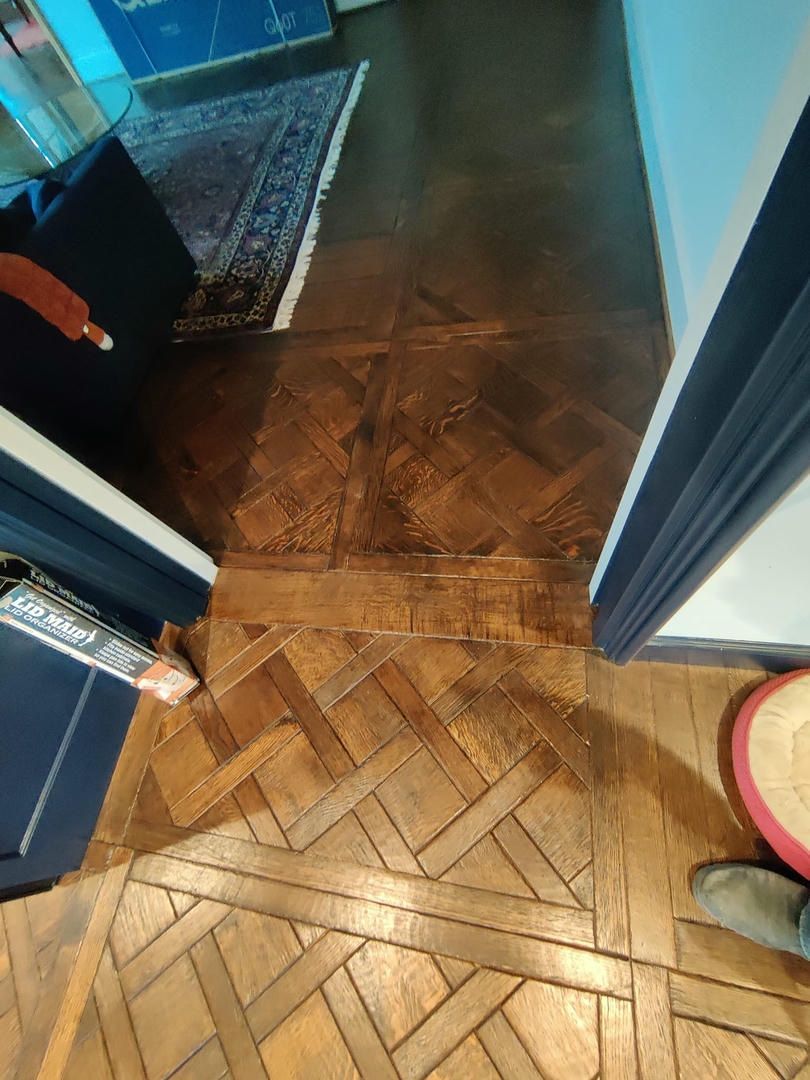 A person is standing on a wooden floor in a hallway.