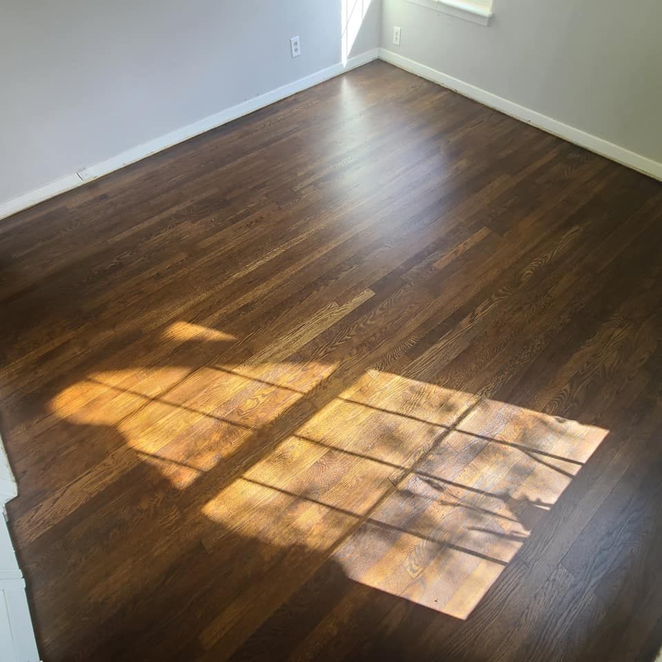 A room with a wooden floor and a window with a shadow on it.