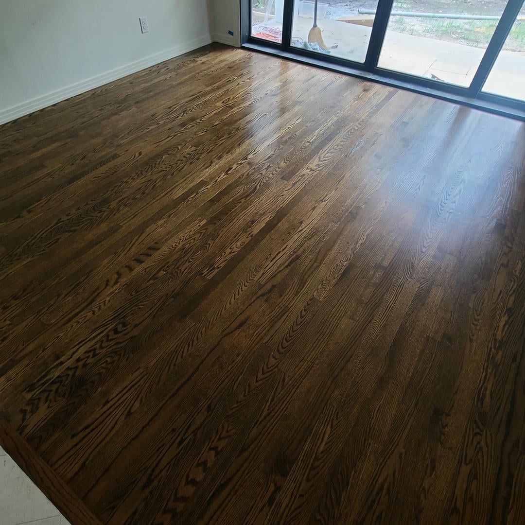 A living room with hardwood floors and a large window.
