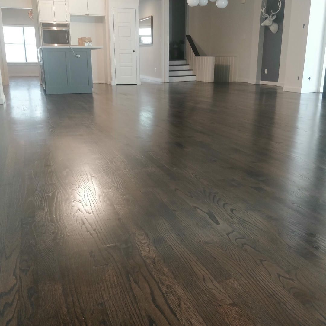 A living room with hardwood floors and a kitchen in the background