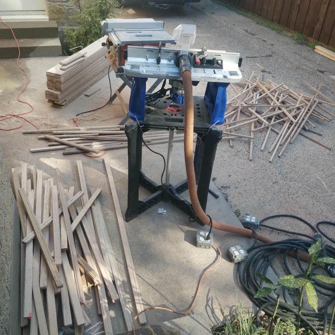 A table saw is sitting on the ground next to a pile of wood