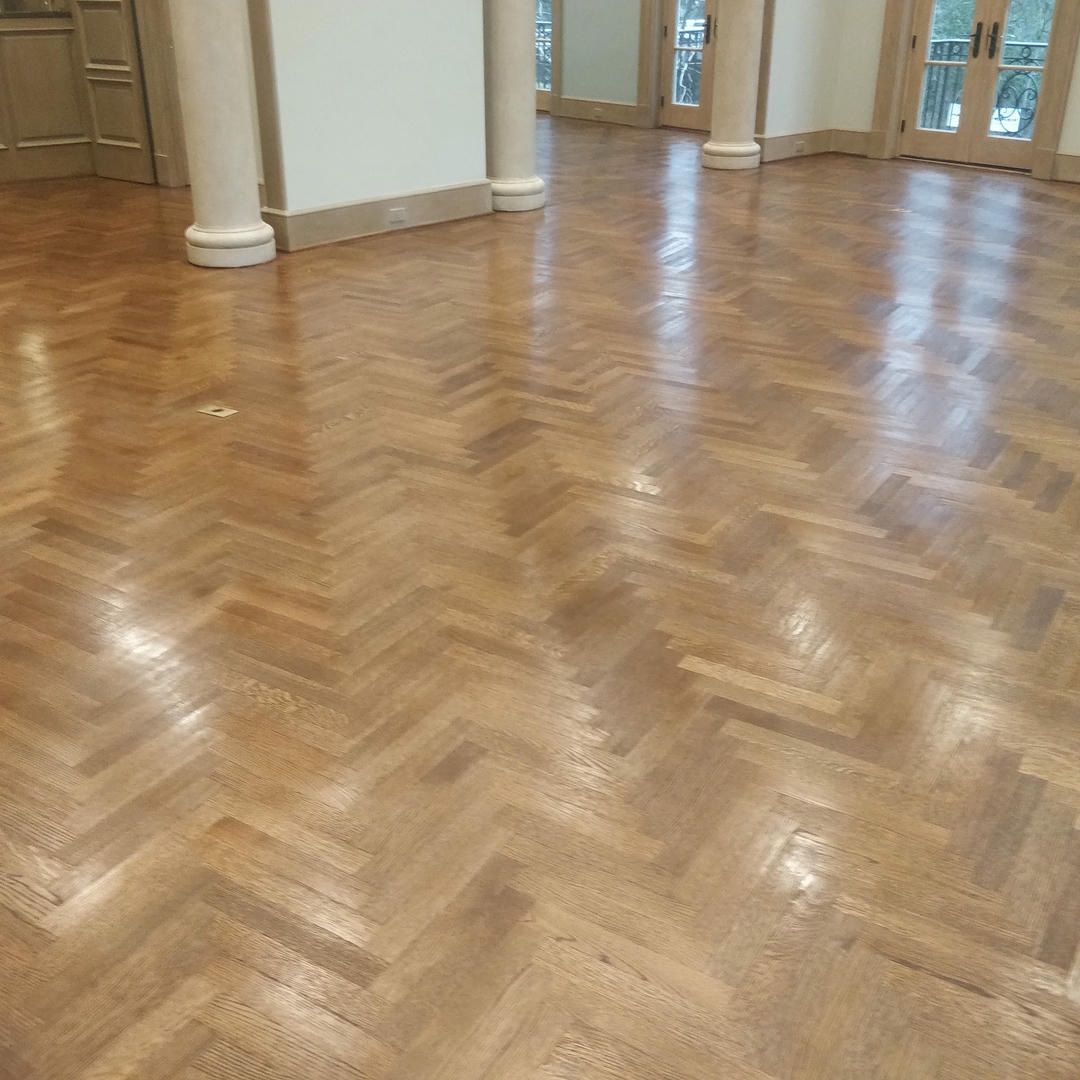 A wooden floor with a herringbone pattern in a room.