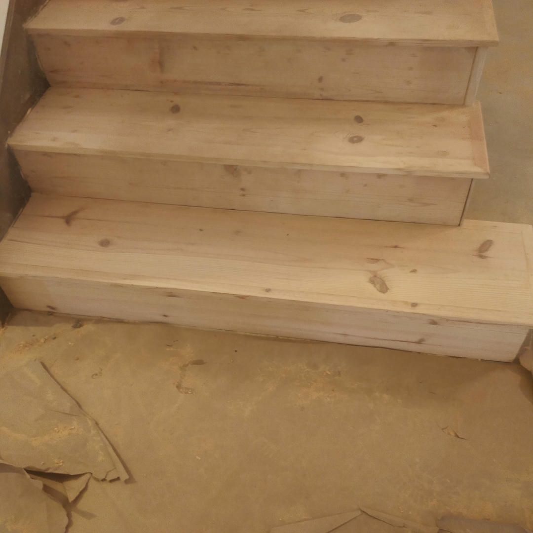 A set of wooden stairs sitting on top of a wooden floor.