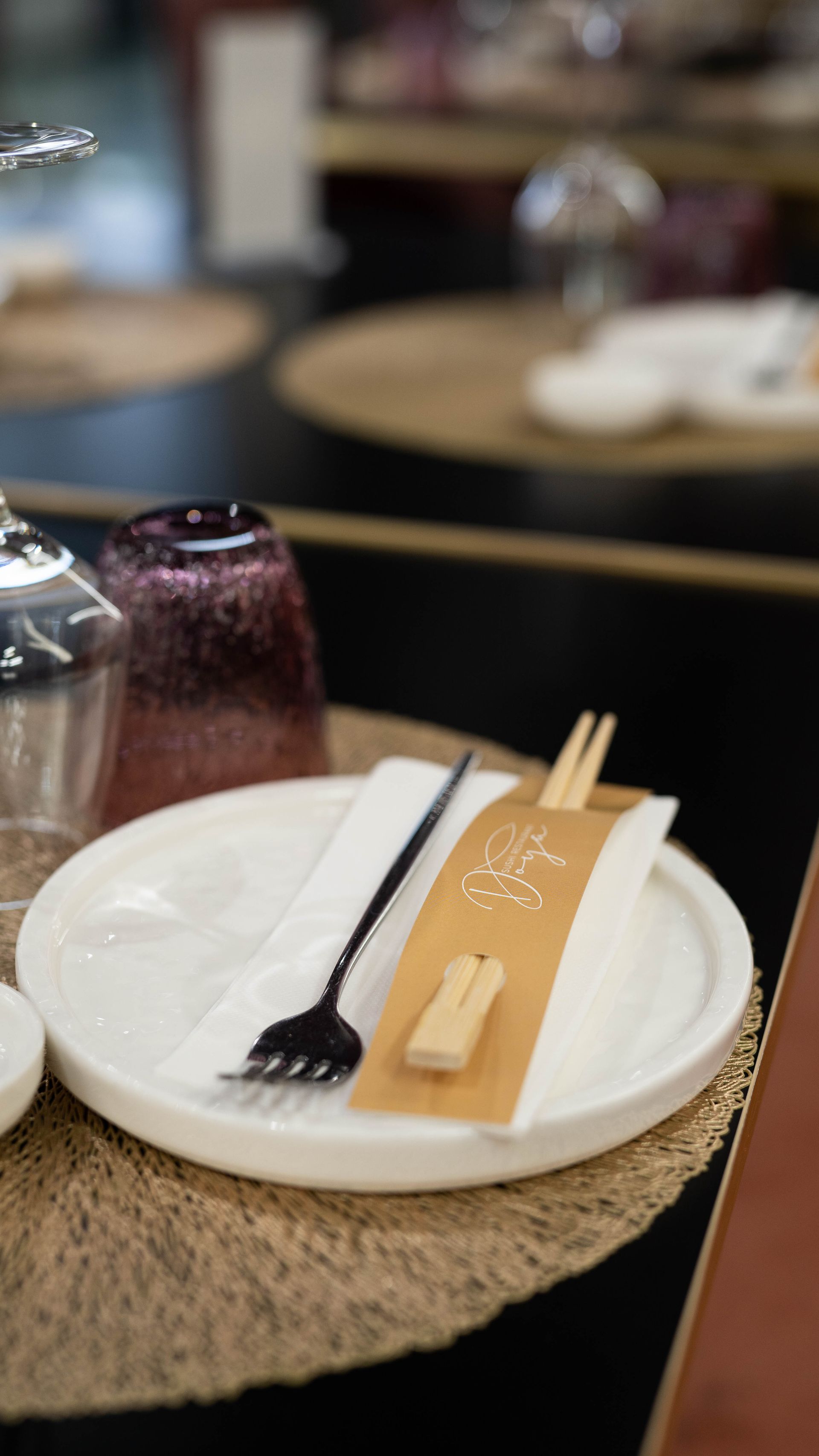 Su un tavolo c'è un piatto con le bacchette e una forchetta.