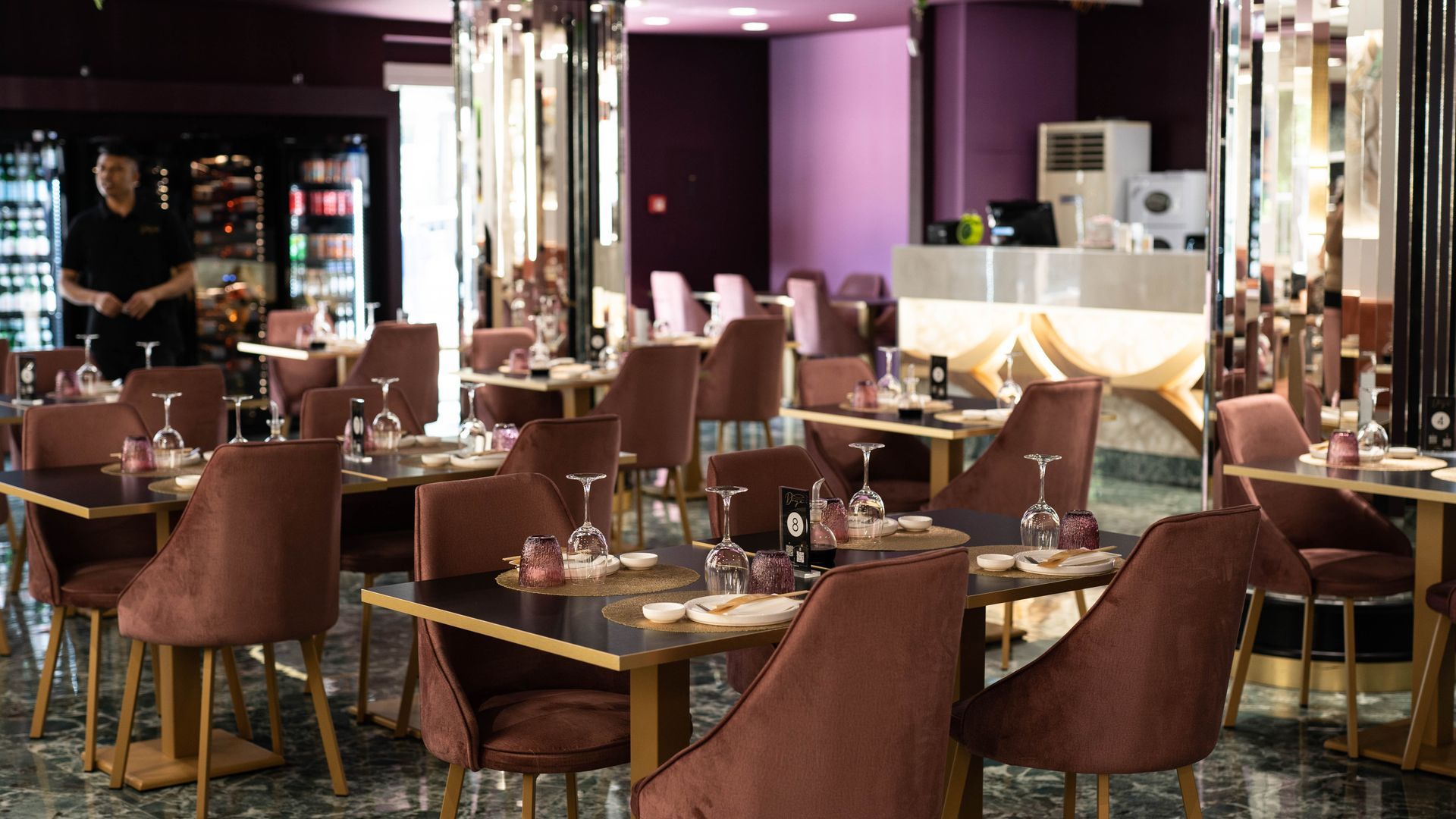 Un ristorante con tavoli e sedie e un uomo in piedi sullo sfondo.