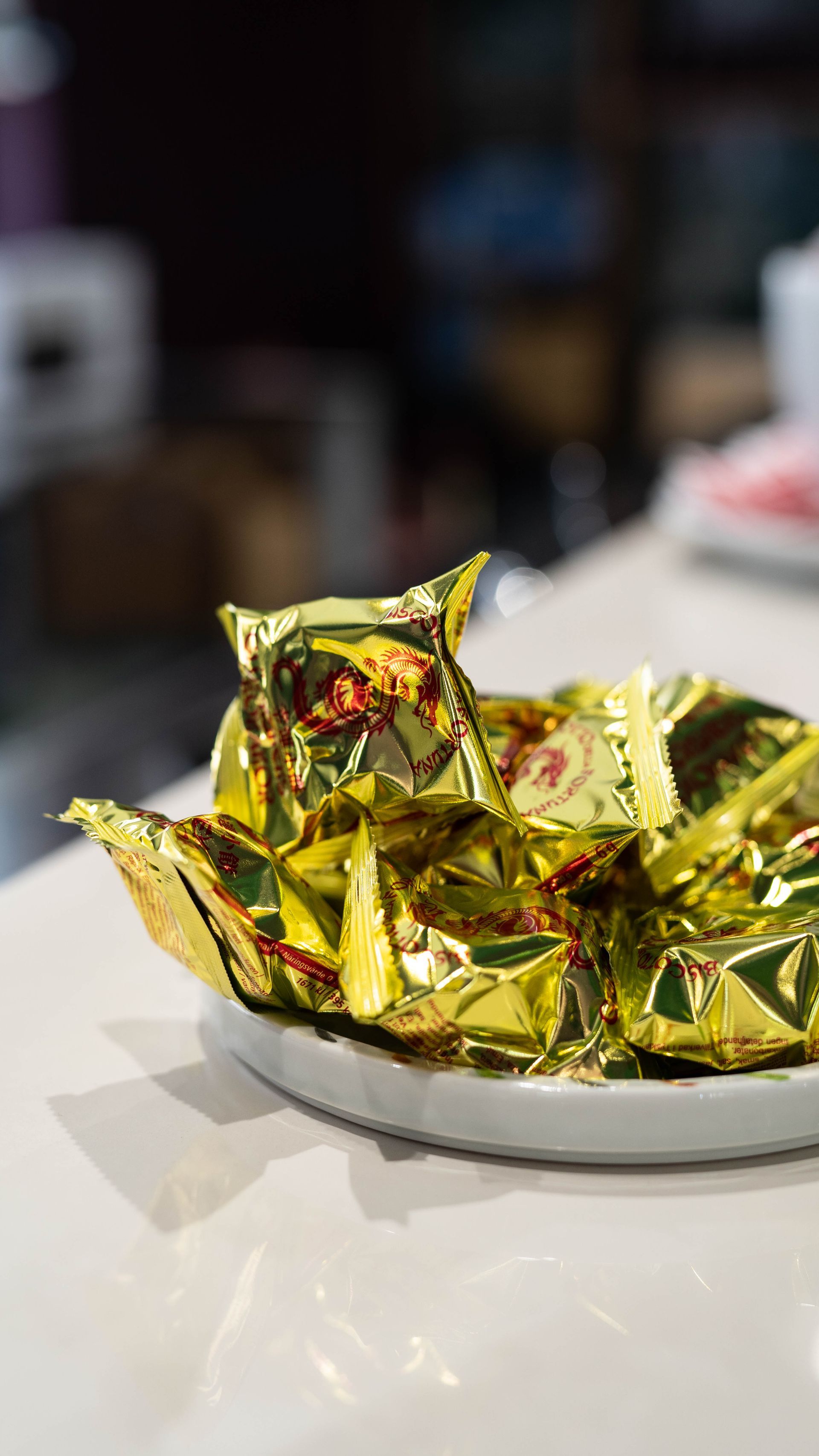 Un piatto bianco sormontato da caramelle avvolte in oro su un tavolo.