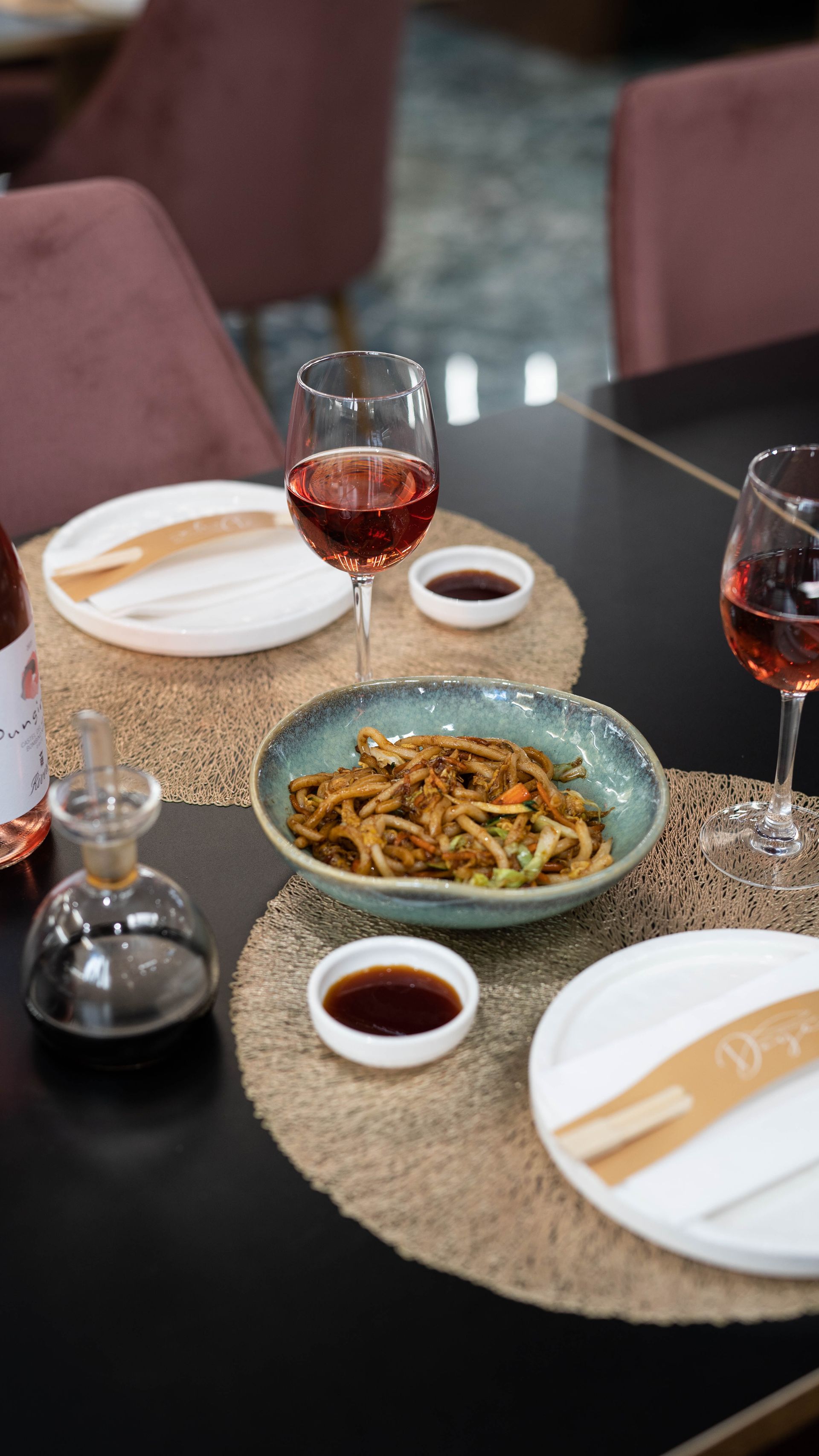 Un tavolo con sopra piatti di cibo e bicchieri di vino.