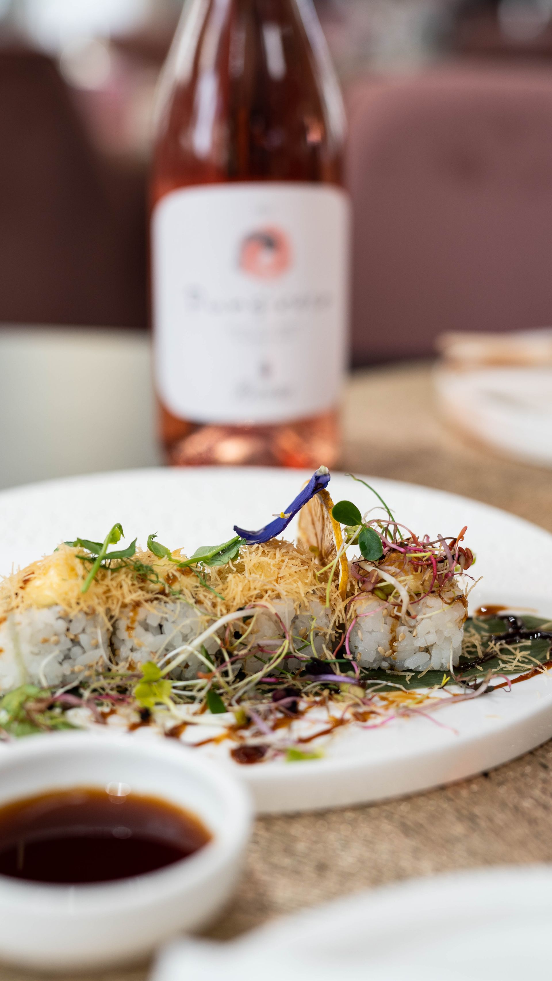 Un primo piano di un piatto di cibo con una bottiglia di vino sullo sfondo.