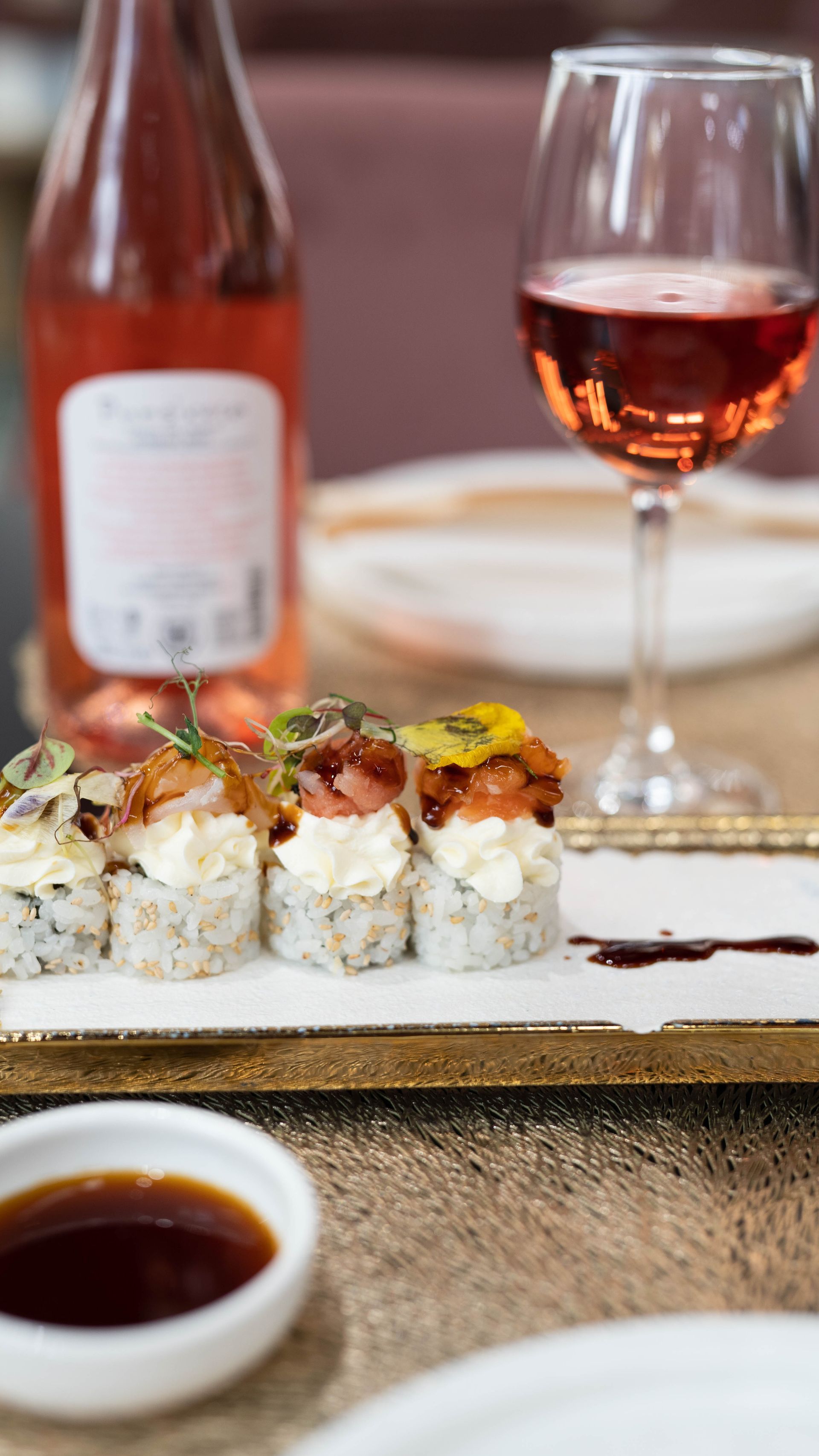 Un vassoio di sushi e un bicchiere di vino su un tavolo.