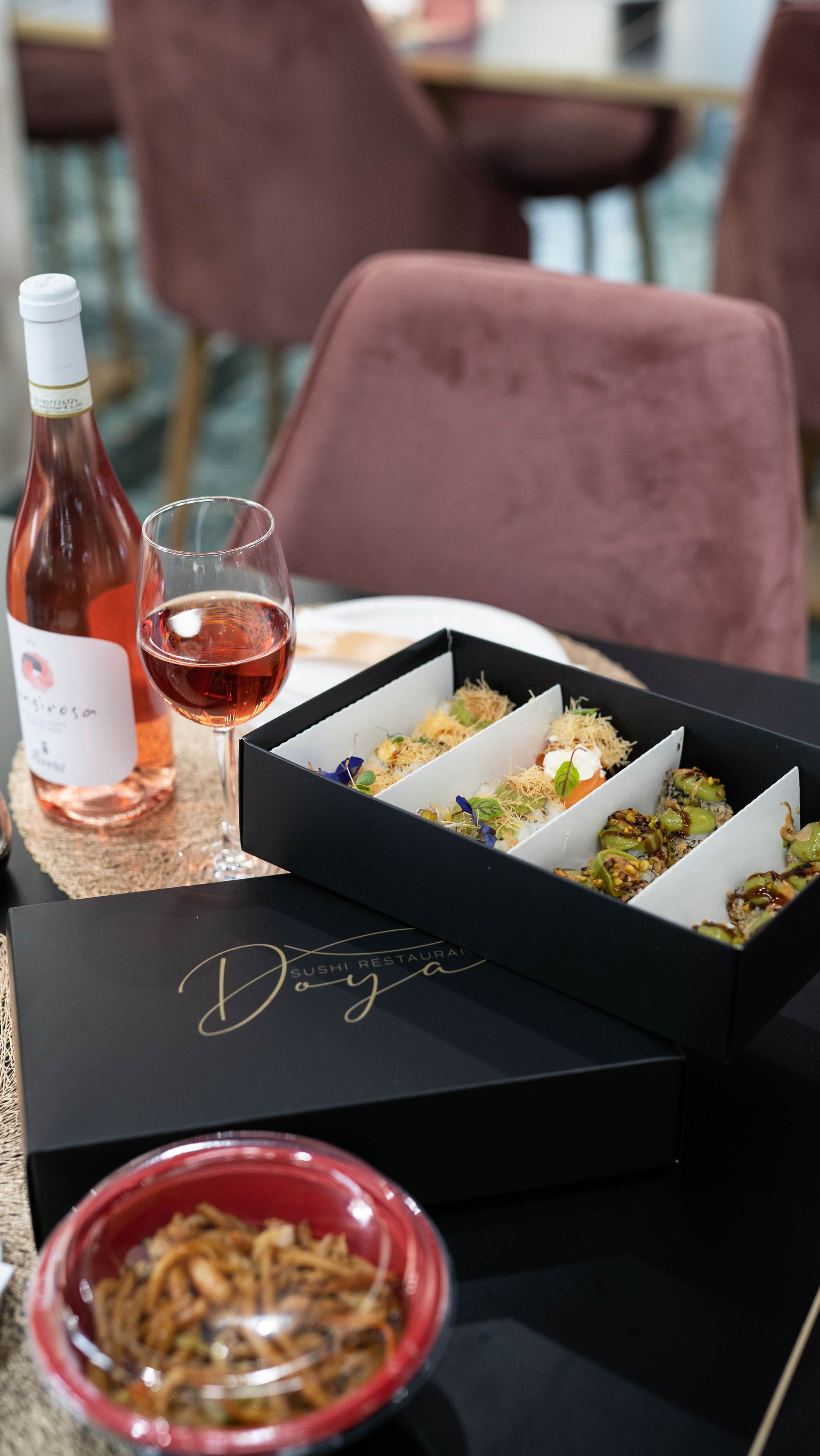 Una scatola di cibo e una bottiglia di vino su un tavolo.