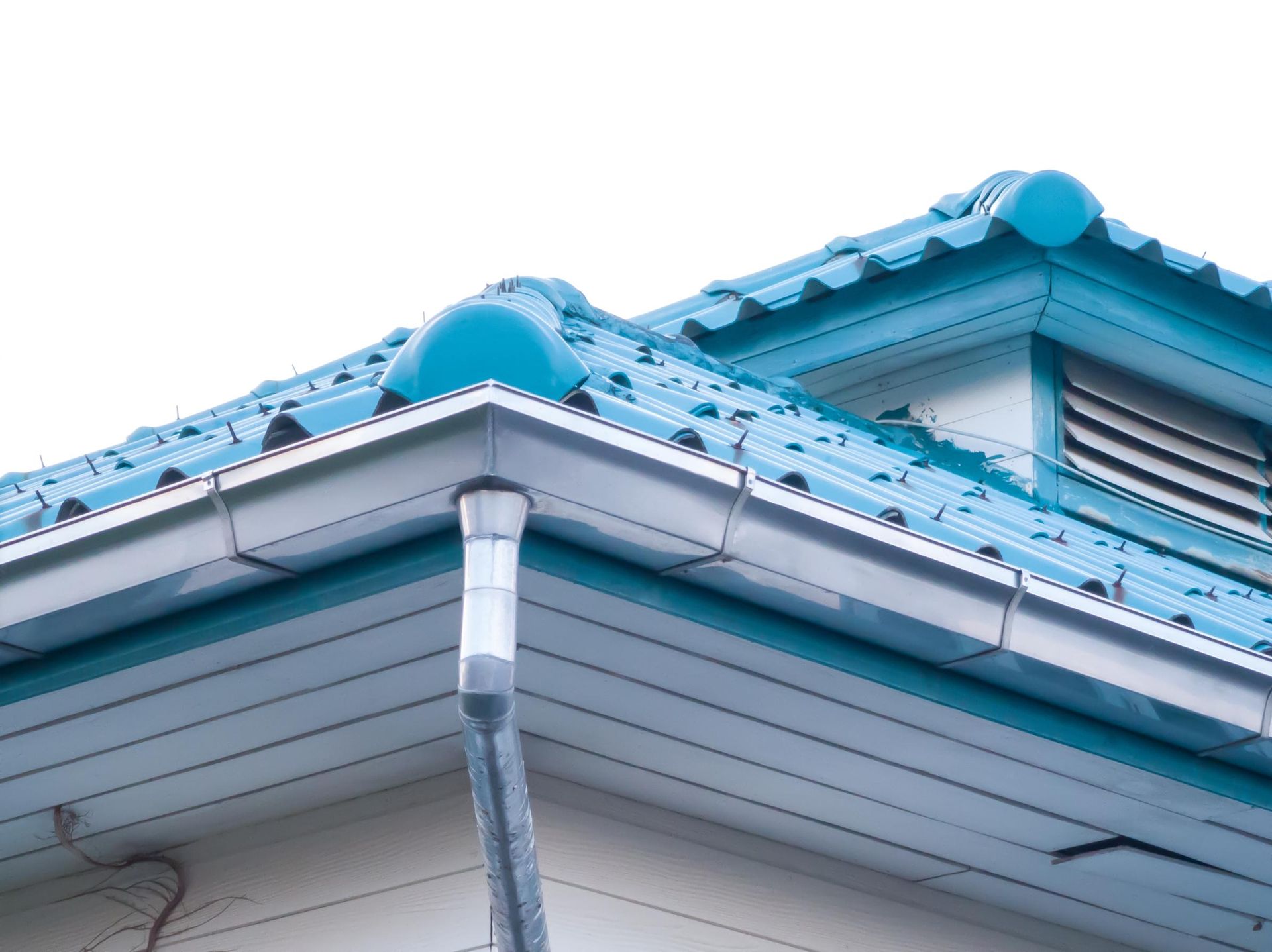 Blue tiled roof with white trim and a gutter, against a white sky.