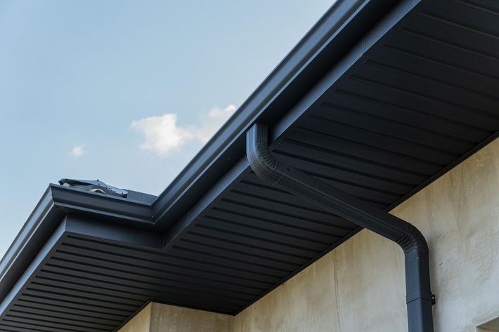 Black gutter system on a building's roof against a blue sky.