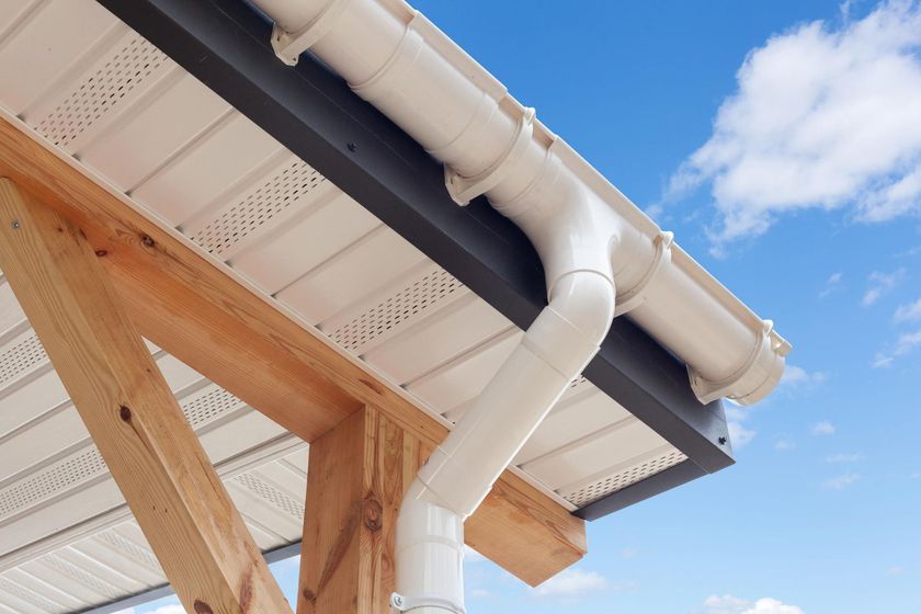 White rain gutter system on a building with a blue sky background.