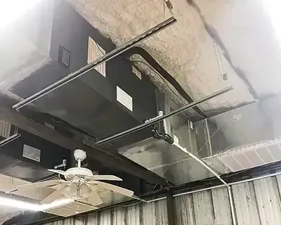Industrial ceiling with ductwork, fan, and insulation; interior of a building.