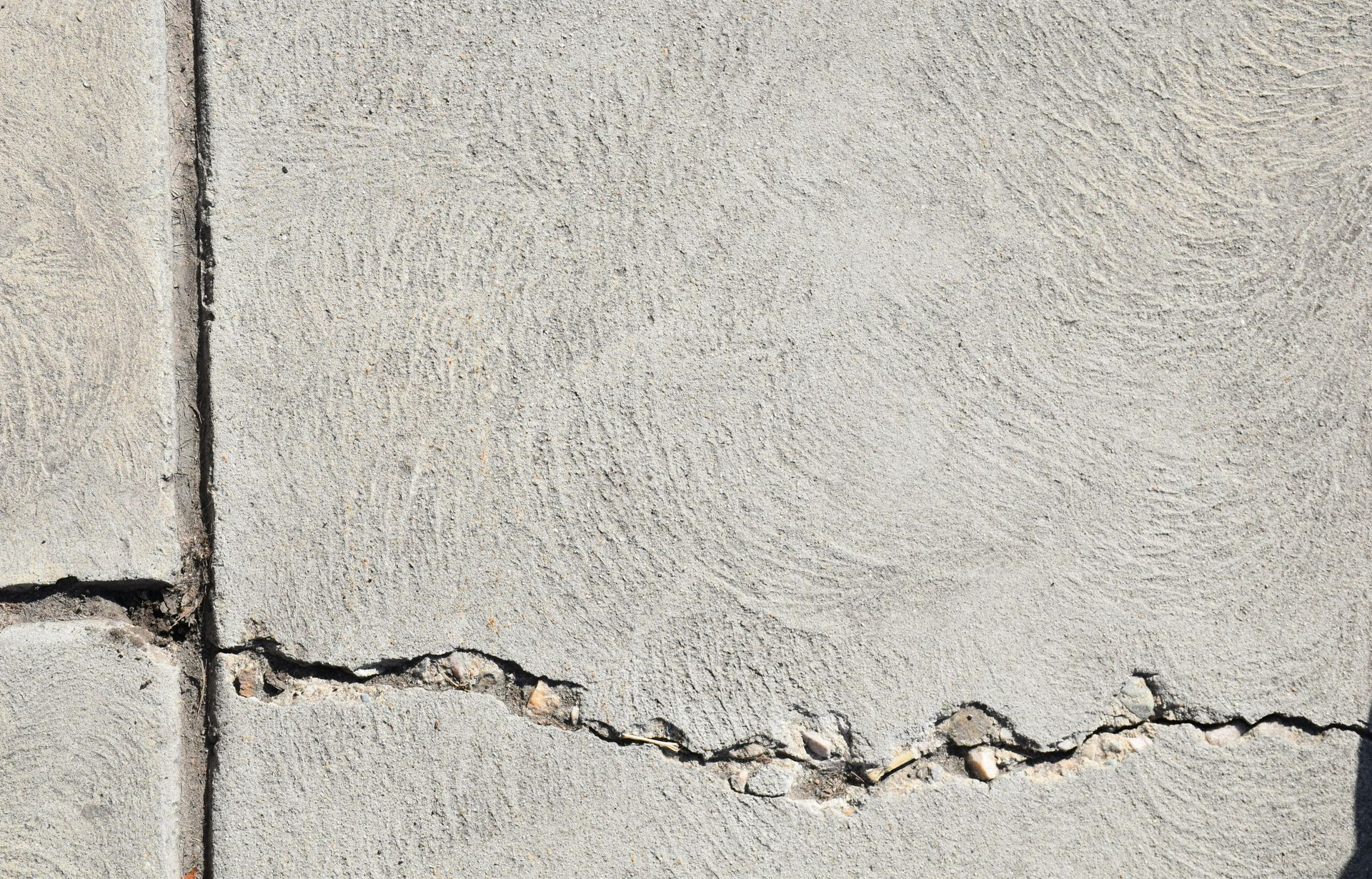 Cracked basement concrete in Lethbridge with visible joint lines; close-up detail.