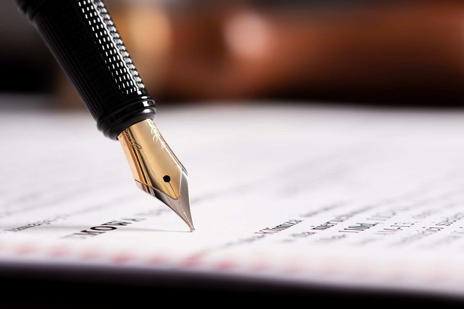 Close-up of a fountain pen tip signing a document on paper. Close-up of a fountain pen tip signing a document on paper.