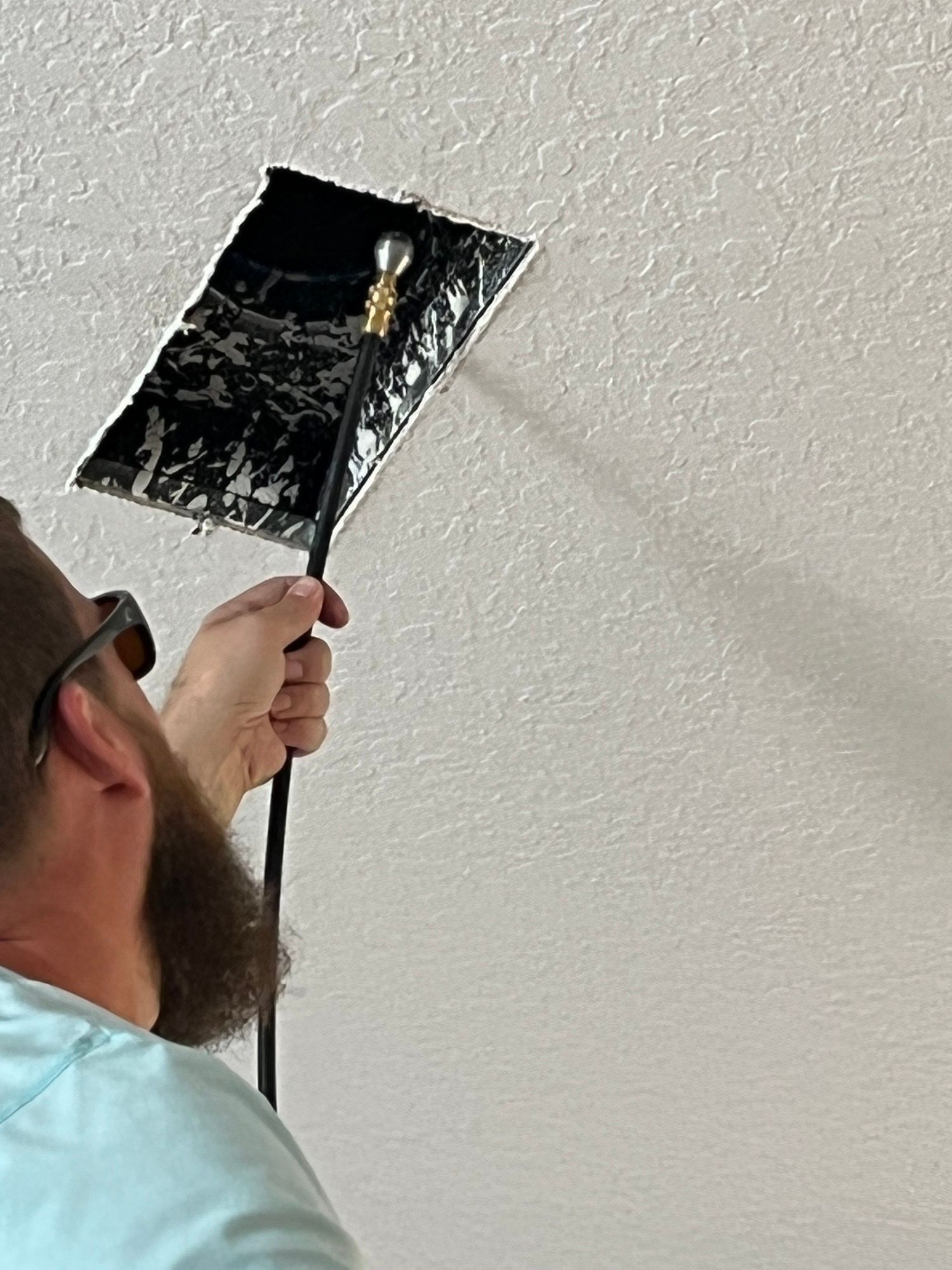 A man is cleaning the ceiling with a brush.