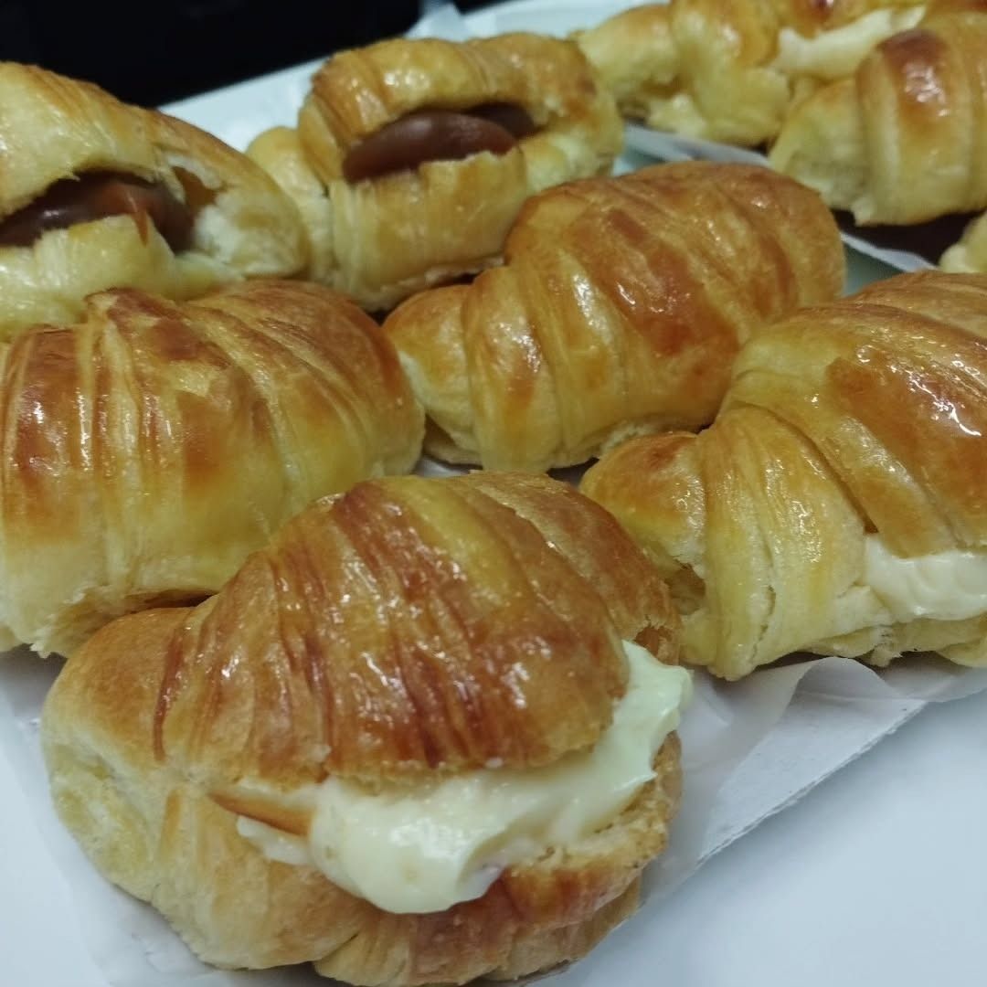 Croissants rellenos de crema y caramelo en una bandeja blanca.