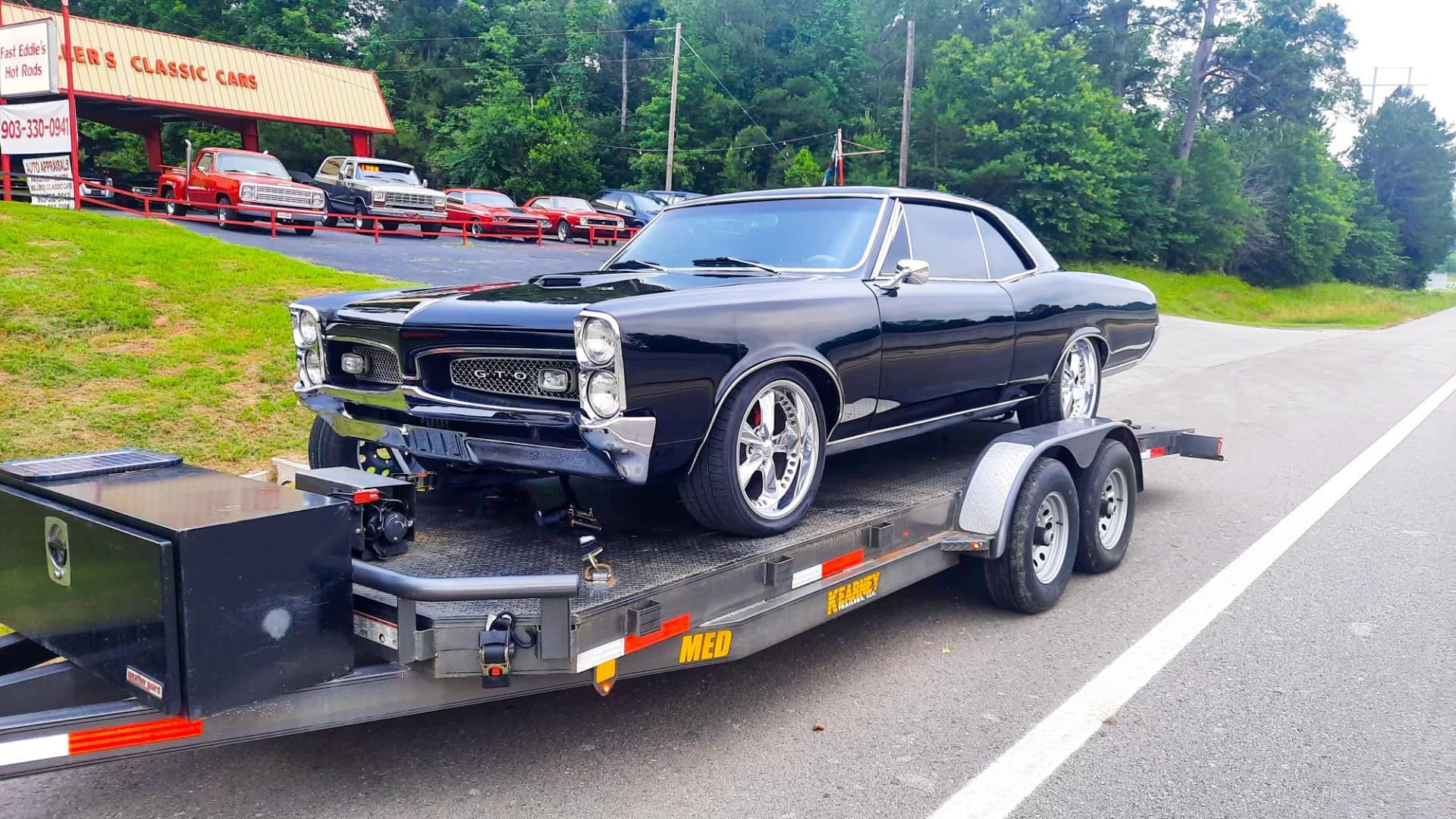 A black car is sitting on top of a trailer.