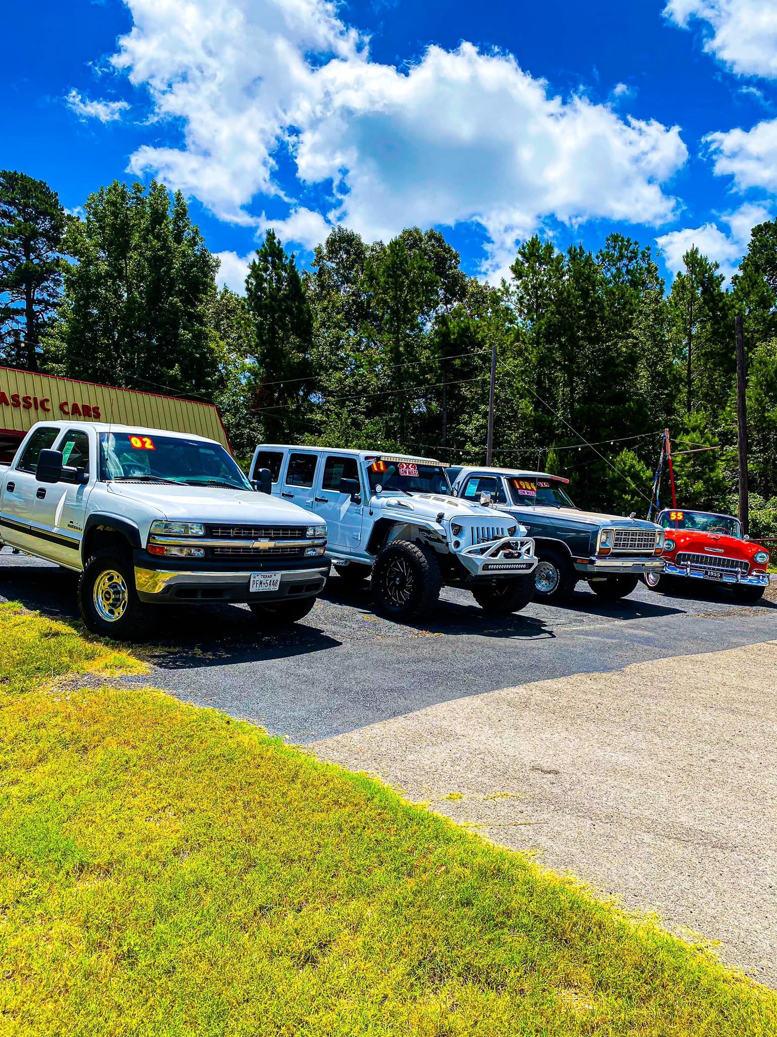 A row of cars are parked in front of a car dealership.