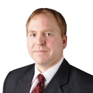 A man in a suit and tie is smiling for the camera