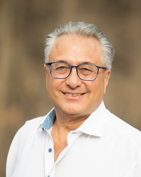 A man in a suit and tie is smiling in front of a bookshelf
