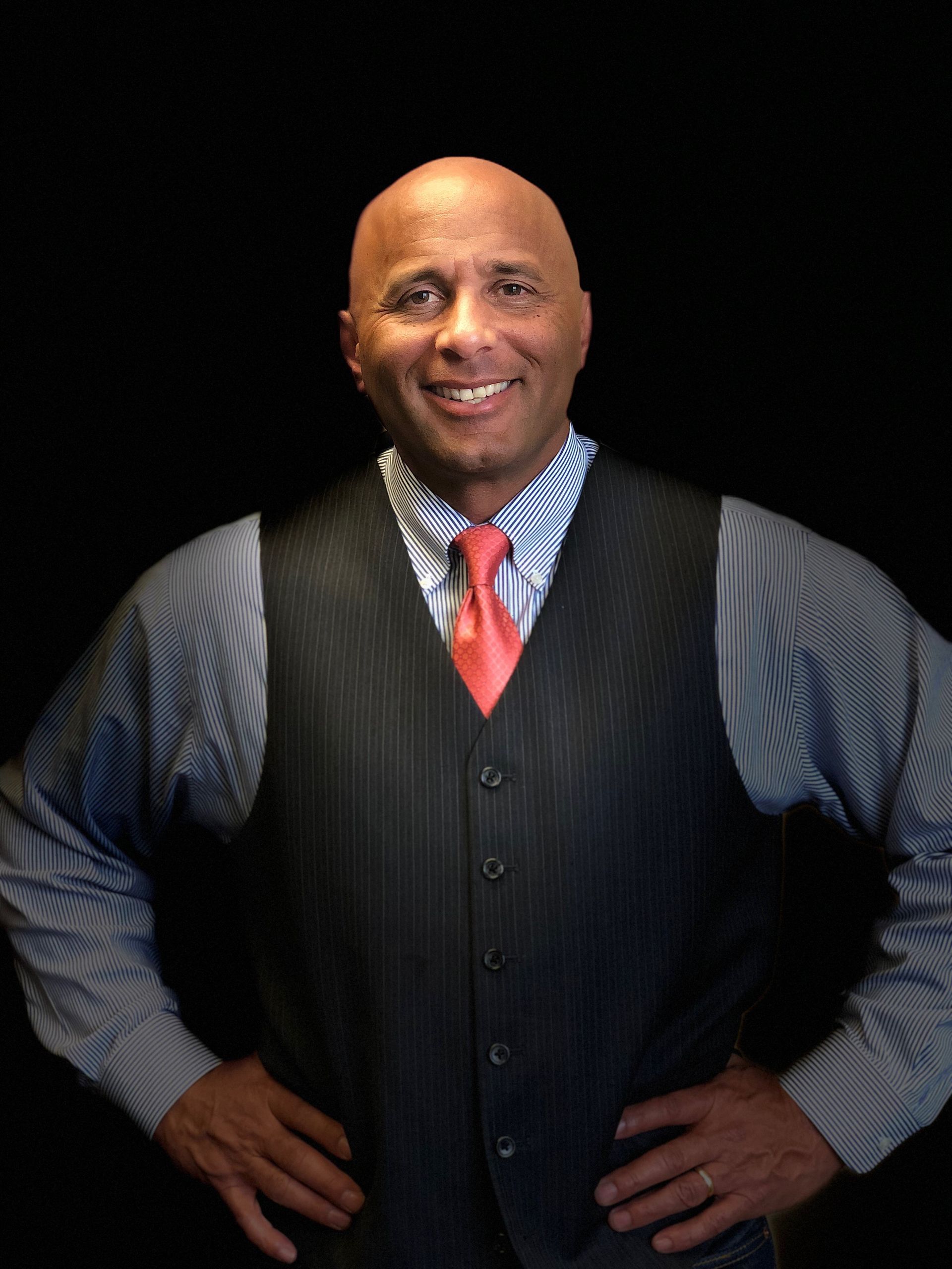 A man in a suit and striped shirt smiles for the camera