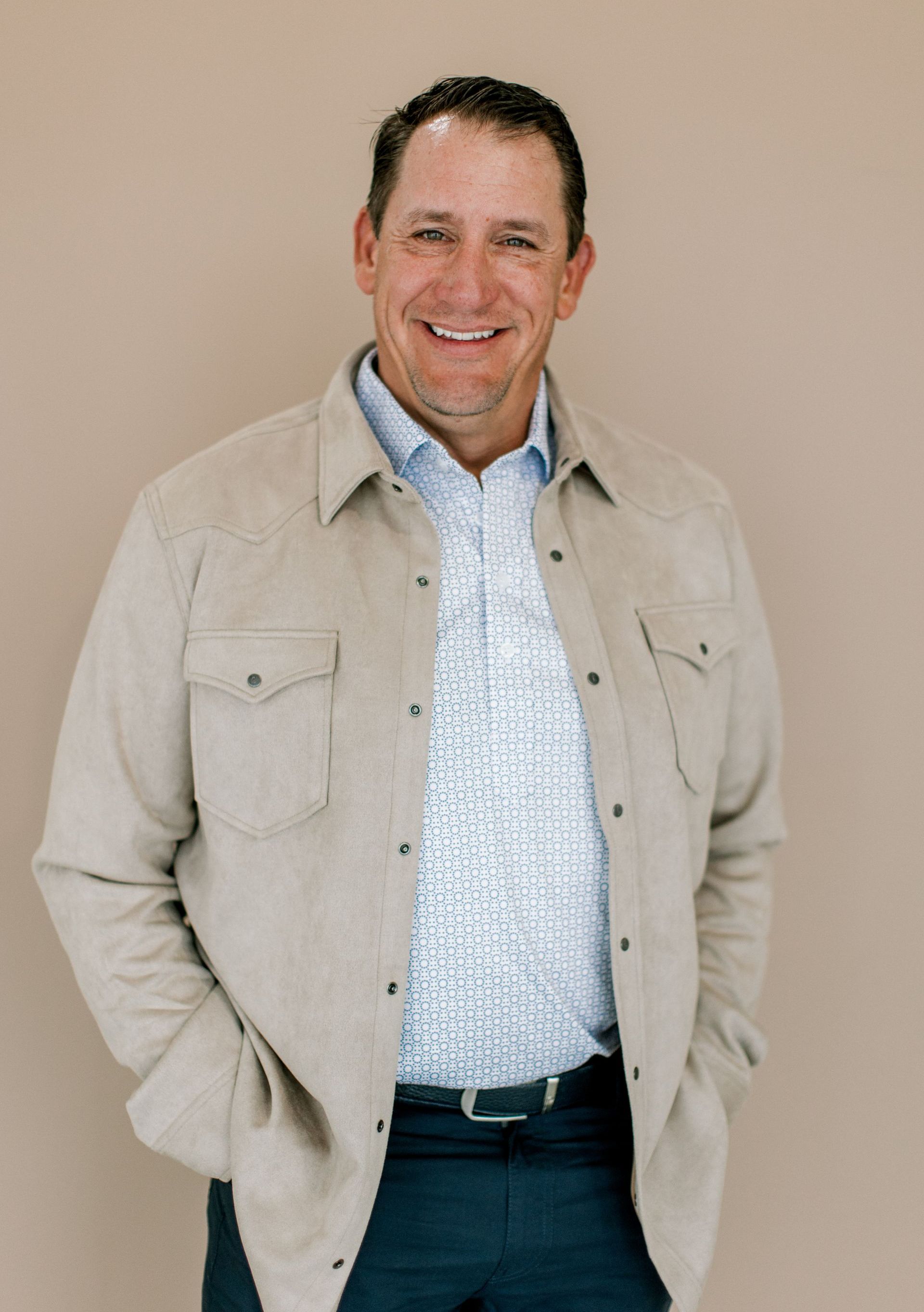 A woman in a blue shirt is smiling in front of a painting.