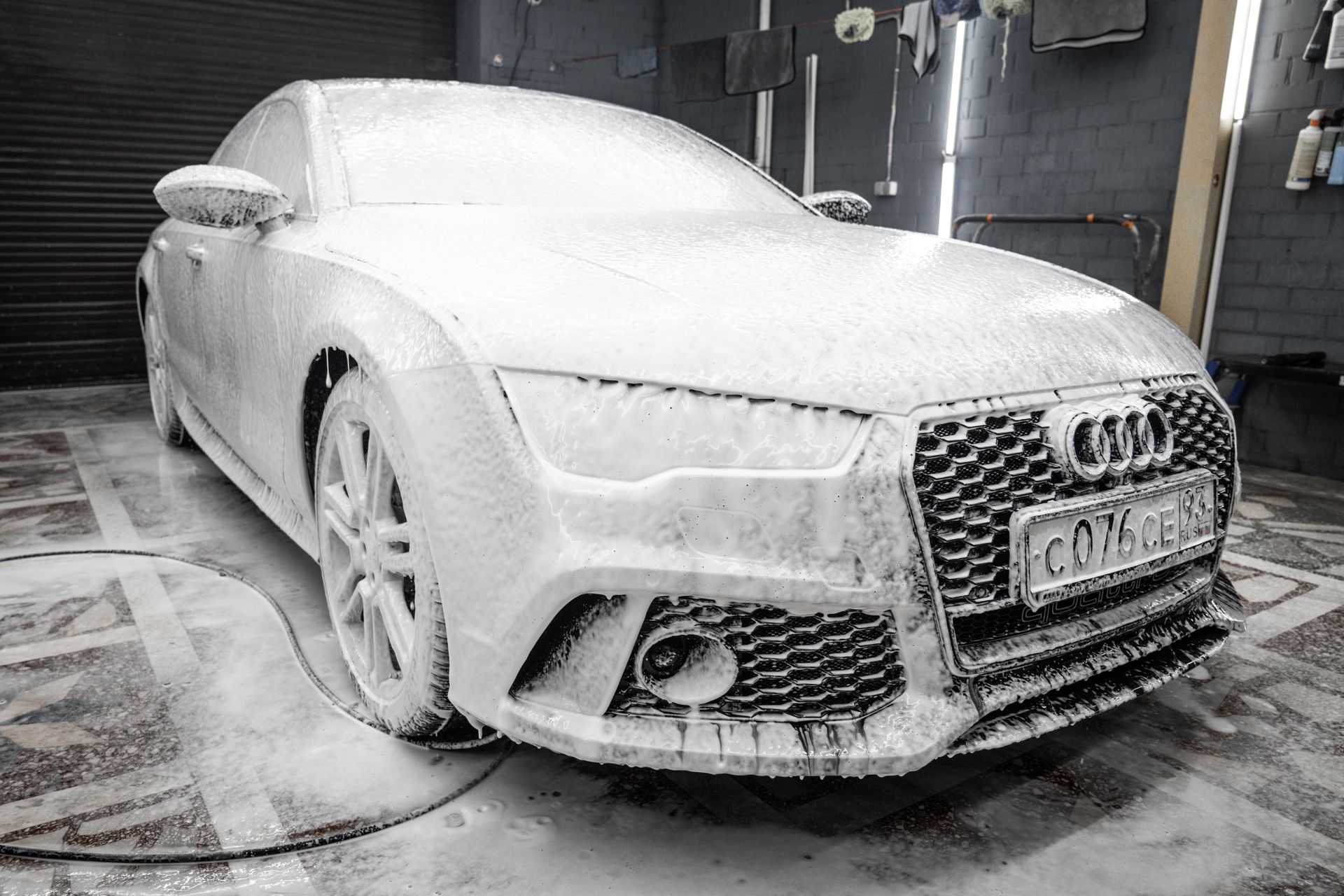 A person polishing a black truck with a green microfiber towel in a well-lit garage, highlighting the vehicle's shine.