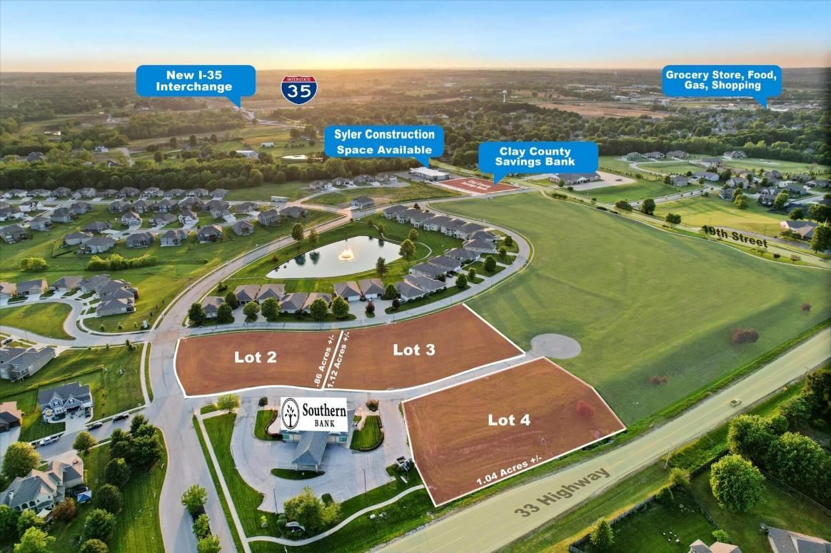 Aerial view of a planned neighborhood with labeled lots, pond, homes, and green fields at sunset.