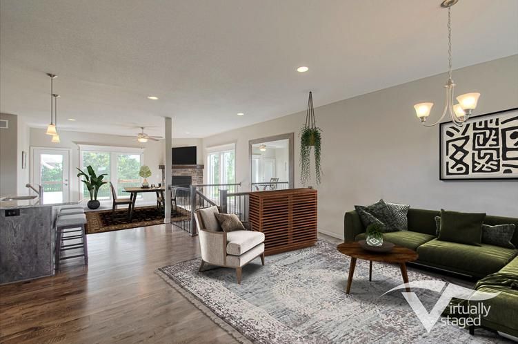 Bright open-concept living room with green sofa, gray rug, and dining area near large windows