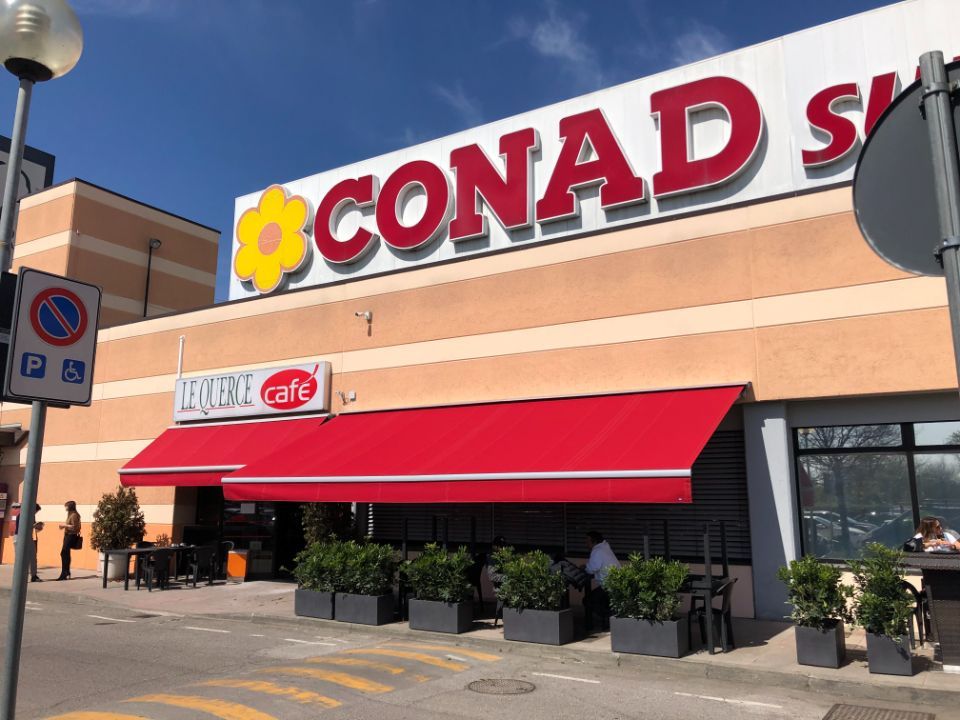 tenda da sole rossa fuori da supermercato Conad