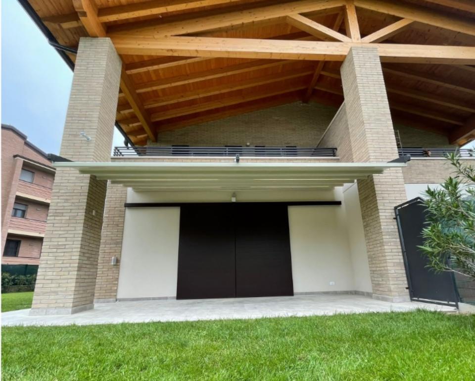 pergotenda fuori da un garage con prato vicino