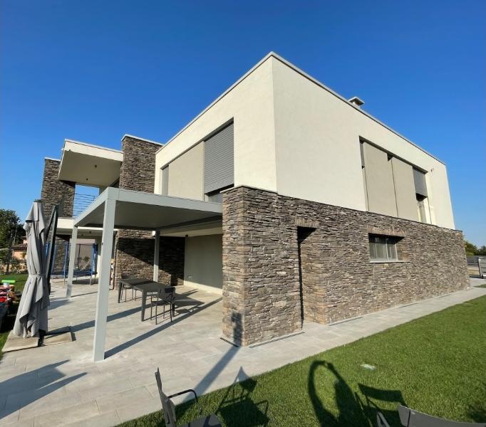 pergola bioclimatica grigia in una casa a due piani con giardino