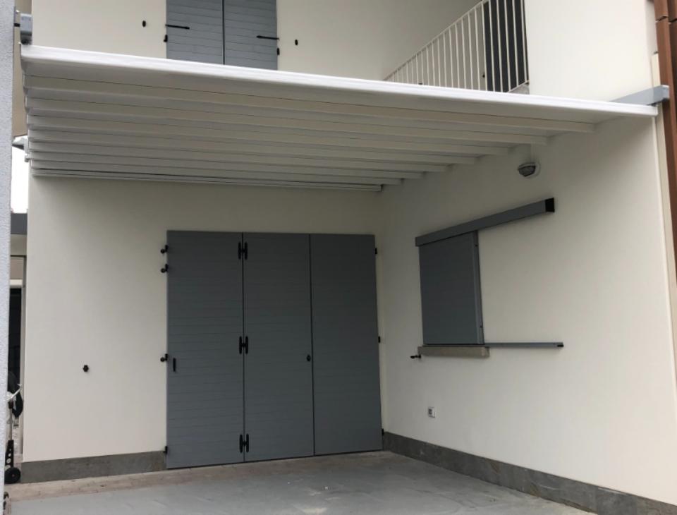 pergotenda bianca in un terrazzo con porta grigia